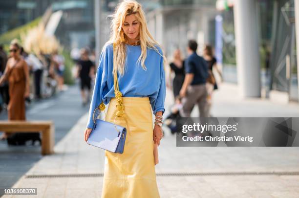 Ada Kokosar wearing yellow skirt with slit, blue top and bag, white ankle boots is seen outside Alberta Ferretti during Milan Fashion Week...