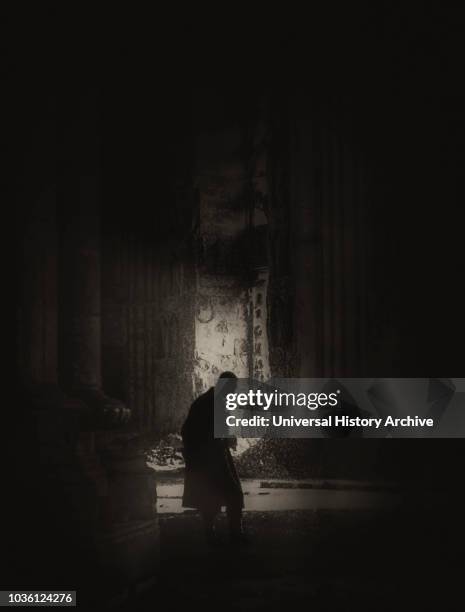 Magic lantern slide shows a silhouetted man stands inside the Cathedral of Reims after the shelling by German troops in 1914; Reims, France