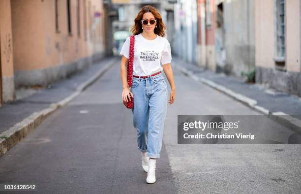 Guest wearing white Balenciaga tshirt, cuffed denim boyfriends jeans, white ankle boots, red Valentino bag, sunglasses during Milan Fashion Week...