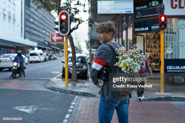 bike messenger carrying flowers in backpack - regarder par dessus son épaule photos et images de collection