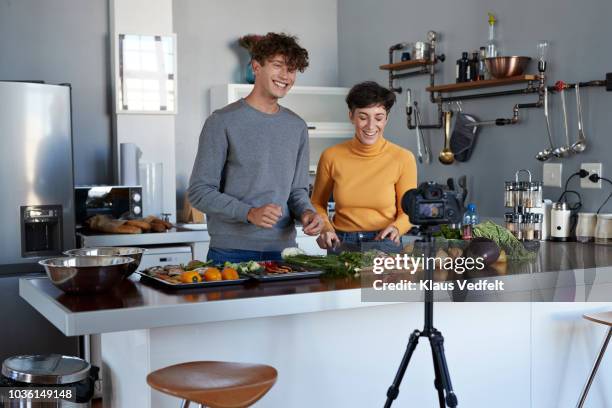 two food vloggers making video while prepping vegetables in kitchen - cooking on camera stock-fotos und bilder