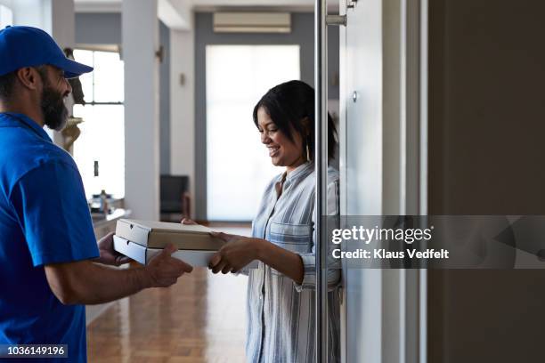 woman receiving pizza from delivery person - pizza delivery stock-fotos und bilder