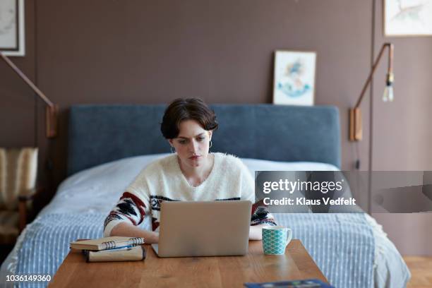 cool young woman sitting in apartment working on laptop - studentenhuis stockfoto's en -beelden