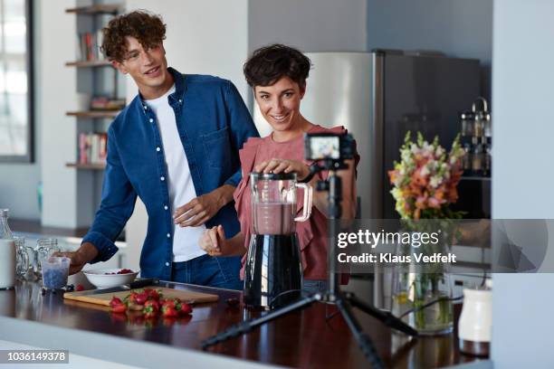 food vloggers making video while blending a berry smoothie - cooking on camera stock-fotos und bilder