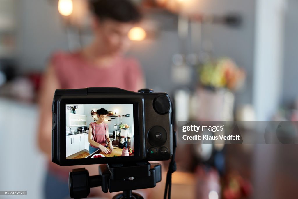 Female food vlogger making video while prepping berries for smoothie