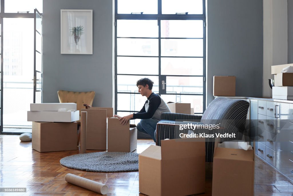 Woman wrapping boxes in stylish apartment