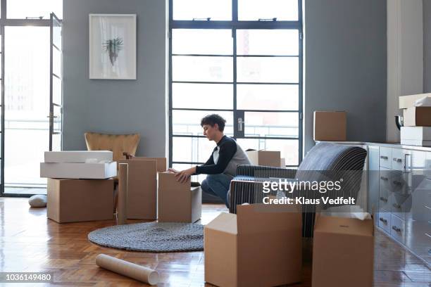 woman wrapping boxes in stylish apartment - bruin pak stockfoto's en -beelden