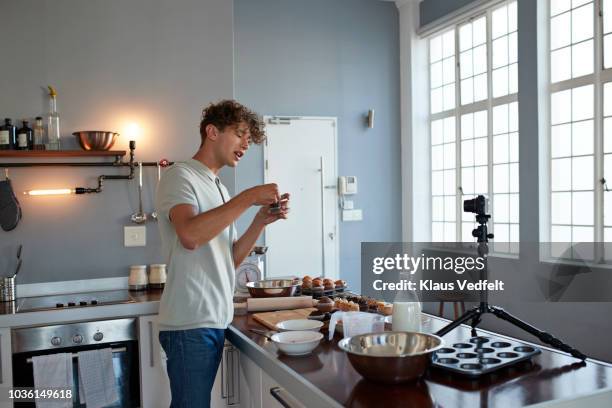 male vlogger making video while baking in kitchen - jeans cake foto e immagini stock