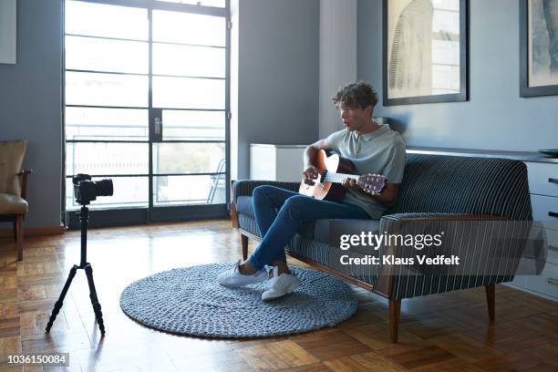 male vlogger recording guitar lesson in stylish apartment - fabolous musician stockfoto's en -beelden