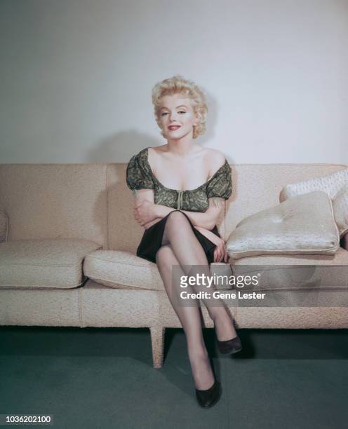 American actress Marilyn Monroe posing on a sofa during a press call to publicise her latest film, Joshua Logan's 'Bus Stop', 1956.