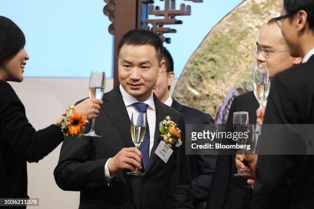 Mu Rongjun, senior vice president and co-founder of Meituan Dianping, center, raises his glass for a toast during the company's listing ceremony at...