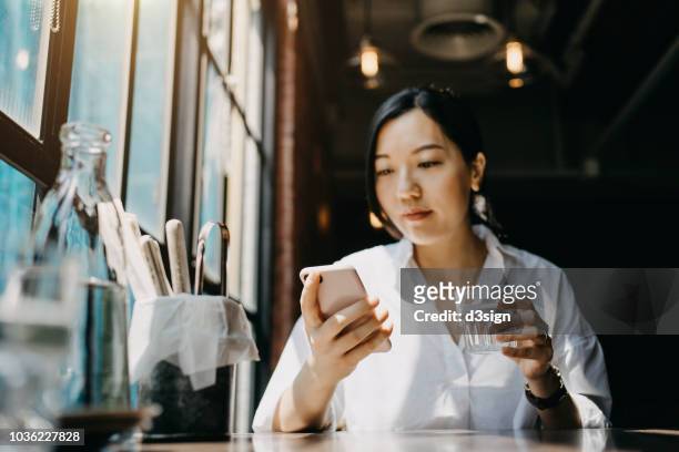 Young woman sitting in restaurant looking at her mobile phone