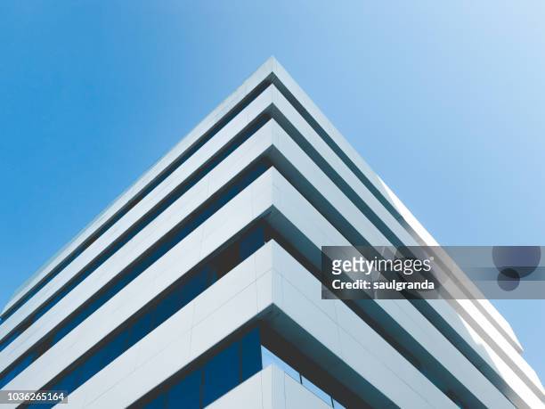 low angle view of building corner against clear blue sky - torre struttura edile foto e immagini stock