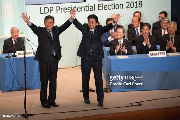 Japan's Prime Minister Shinzo Abe celebrates with Shigeru Ishiba, the former defence minister who ran against him, after winning the Liberal...