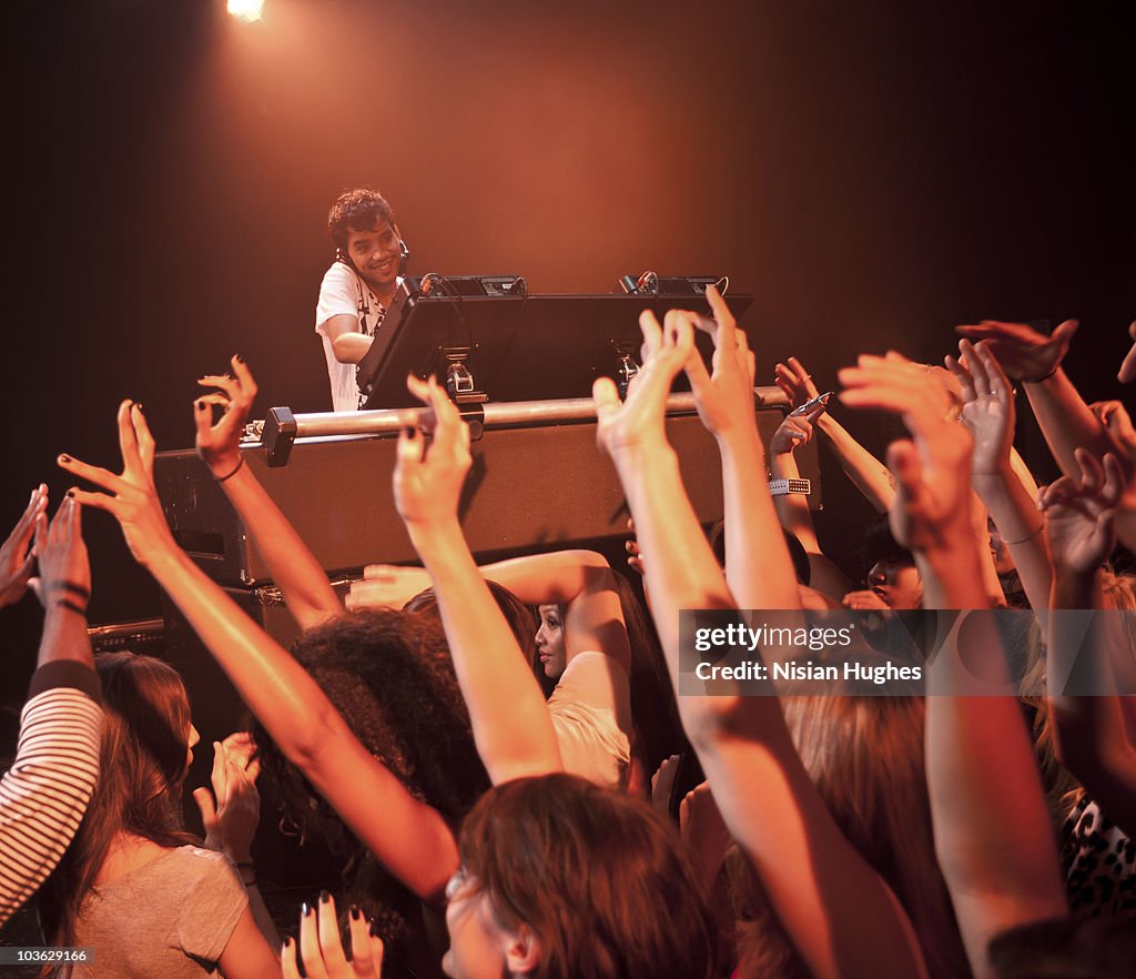 DJ spinning at nightclub surrounded by crowd