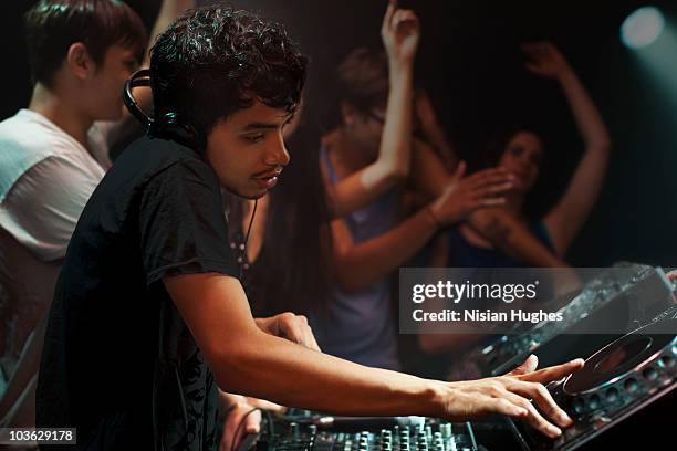 dj spinning at nightclub surrounded by crowd - dj de club fotografías e imágenes de stock