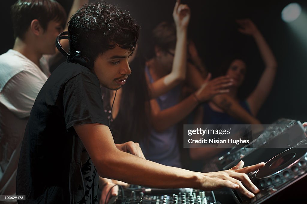 DJ spinning at nightclub surrounded by crowd