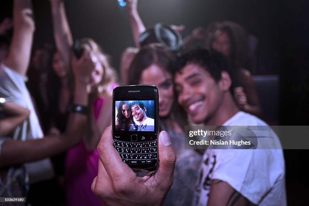 Couple taking a cell phone photo in a nightclub