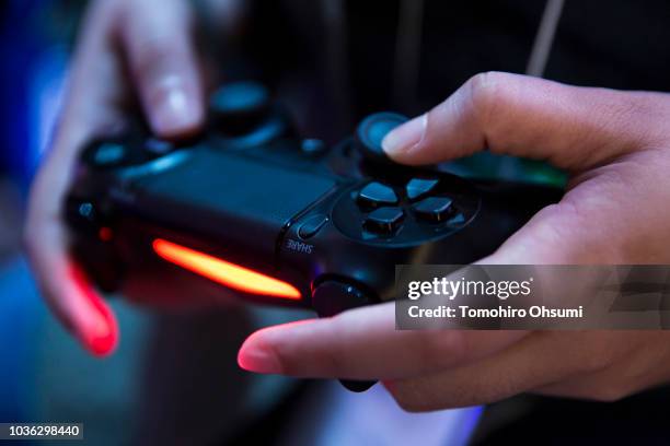 An attendee plays a video game on the PlayStation 4 video game console in the Sony Interactive Entertainment booth during the Tokyo Game Show 2018 on...