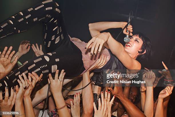 woman singing into microphone while crowd surfing - stage diving stock-fotos und bilder