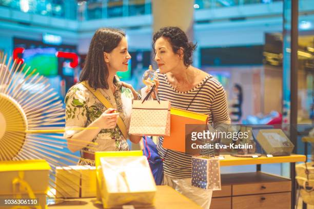 mother and her adult daughter are shopping together - choosing perfume stock pictures, royalty-free photos & images