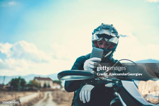 motorradfahrer, die anpassung der navigations auf dem handy auf seeseite - biker stock-fotos und bilder