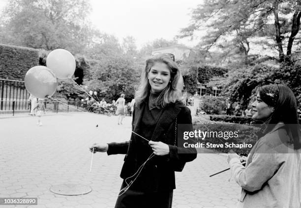 American model and actress Candice Bergen smiles as she holds a pair of balloons during a visit to the Central Park Children's Zoo, New York, New...