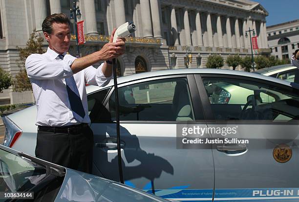 San Francisco mayor Gavin Newsom holds a power cable before test driving a plug-in version of the popular Toyota Prius that is one of four on loan to...