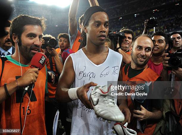 Ronaldinho of AC Milan and formerly of Barcelona gives away his boots to a fan at the Joan Gamper Trophy match between Barcelona and AC Milan at Camp...