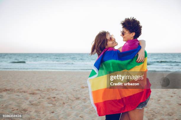girls posing with lgbtqi flag on beach - gay sunglasses stock pictures, royalty-free photos & images