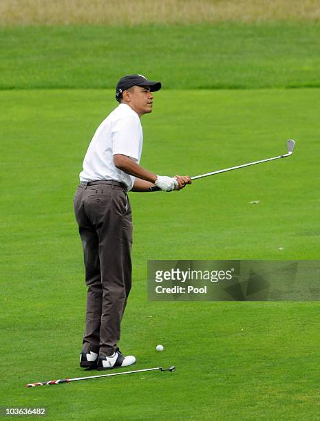 President Barack Obama practices a chip shot into the green while playing the ninth hole at Mink Meadows Golf Club August 25, 2010 while vacationing...