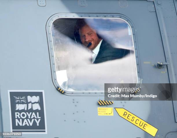 Prince Harry, Duke of Sussex looks out of the window of a Royal Navy Wildcat Maritime Attack Helicopter as departs The Royal Marines Commando...