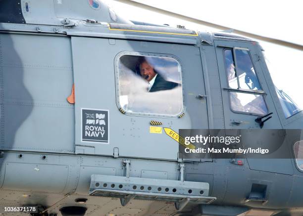 Prince Harry, Duke of Sussex looks out of the window of a Royal Navy Wildcat Maritime Attack Helicopter as departs The Royal Marines Commando...