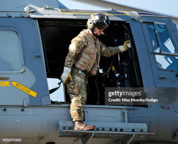 Royal Marines Commando hangs out of the open door of a Royal Navy Wildcat Maritime Attack Helicopter as it departs The Royal Marines Commando...