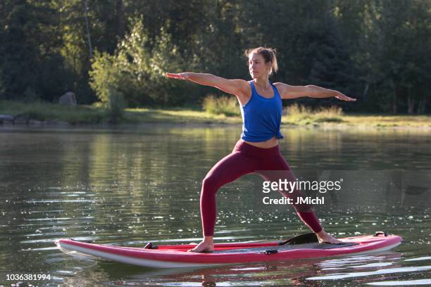 paddle board yoga - practioners enjoy serenity of paddleboard yoga stockfoto's en -beelden