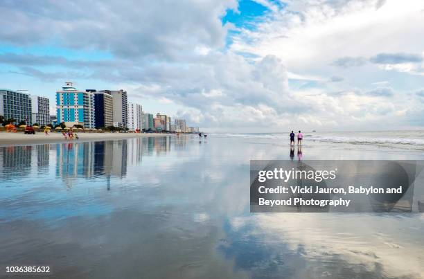 two people walking along shore reflections at myrtle beach, south carolina - myrtle beach boardwalk stock pictures, royalty-free photos & images