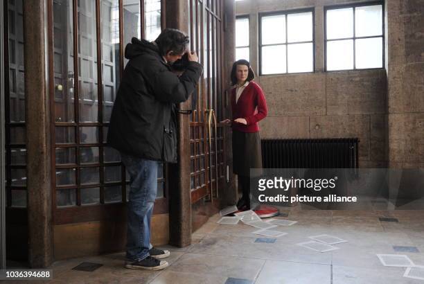 Man photographs the wax figure of Sophie Scholl from the Berlin Madame Tussaud's wax figure museum standing at a back door of the Ludwig Maximilian...