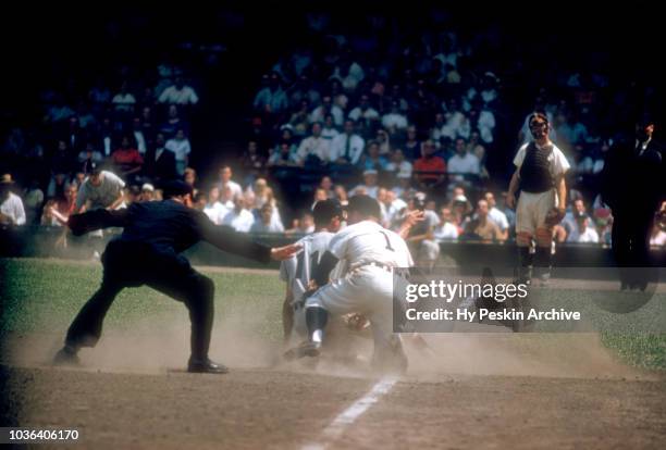 Luis Aparicio of the Chicago White Sox slides under the tag by third baseman Eddie Yost of the Detroit Tigers as umpire Bill McKinley is there to...