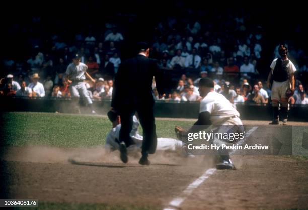 Luis Aparicio of the Chicago White Sox slides under the tag by third baseman Eddie Yost of the Detroit Tigers as umpire Bill McKinley is there to...