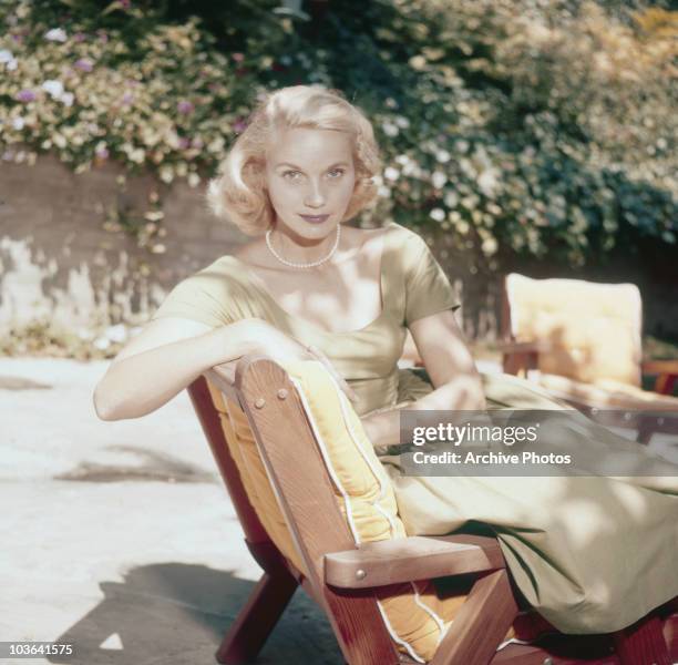 Actress Eva Marie Saint pictured seated on a sun lounger in a garden, USA, circa 1950. Saint is wearing a light green dress and a pearl necklace.