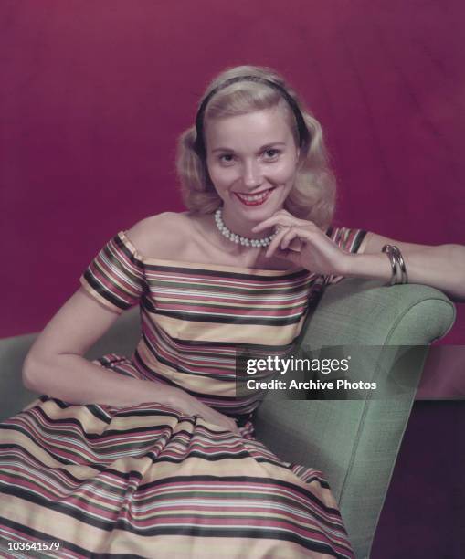 Actress Eva Marie Saint pictured smiling and seated with her left hand, supporting her chin, USA, circa 1950. Saint is wearing a striped...