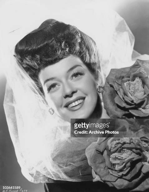 Actress Rosalind Russell pictured smiling with a lace veil covering her head, USA, circa 1937.
