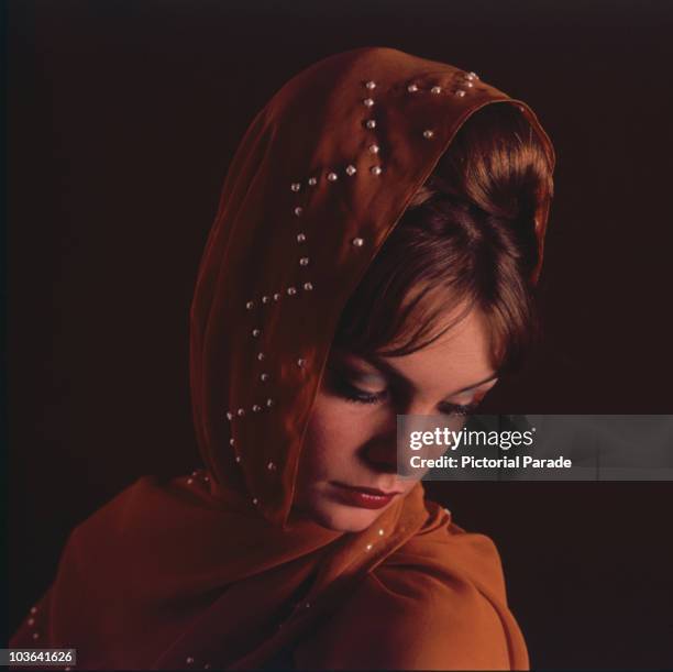 Model Jean Shrimpton pictured wearing a pearl-studded head scarf, Great Britain, circa 1960.