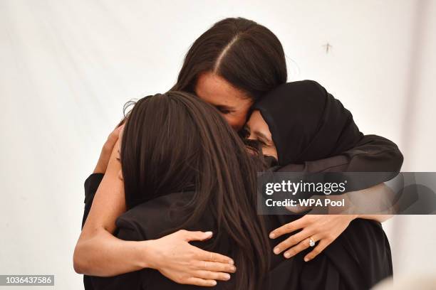 Meghan, Duchess of Sussex embraces women at an event to mark the launch of a cookbook with recipes from a group of women affected by the Grenfell...