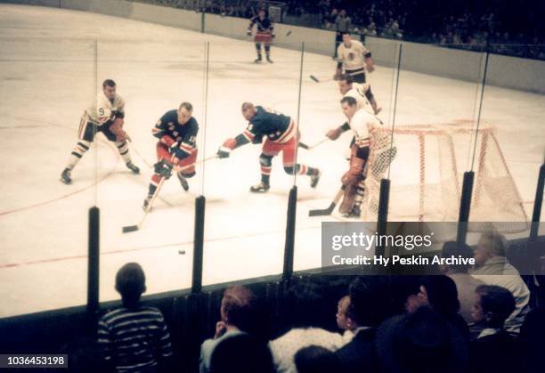 Andy Hebenton of the New York Rangers goes after the puck as goalie Glenn Hall and Nick Miskoski of the Chicago Blackhawks defend the net during an...