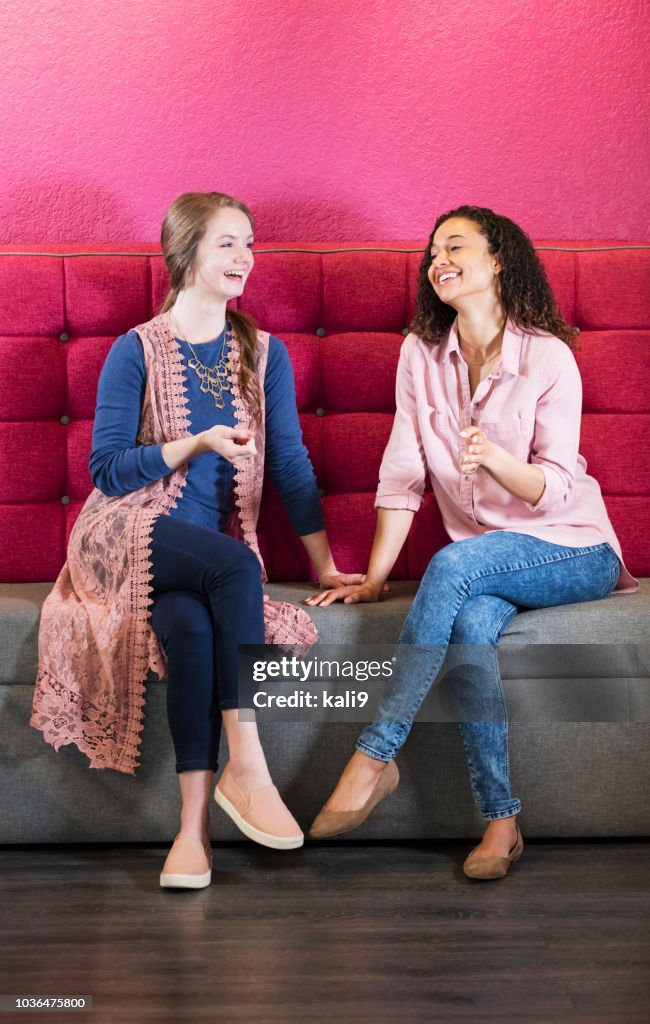 Zwei junge Frauen sitzen auf dem Sofa im Gespräch