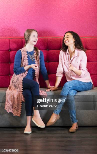 zwei junge frauen sitzen auf dem sofa im gespräch - young women only stock-fotos und bilder