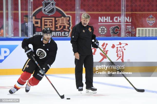 Mark Giordano of the Calgary Flames skates around head coach Bill Peters during practice at the Universiade Sports Center on September 14, 2018 in...