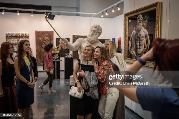 People pose for a selfie with Hercules Selfie an artwork by Emre Yusufi on display at Contemporary Istanbul on September 20, 2018 in Istanbul,...