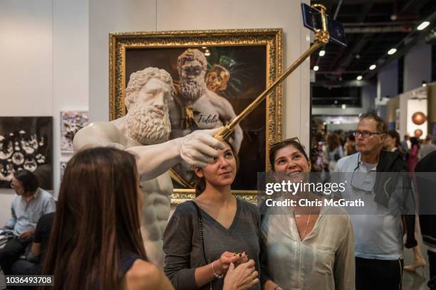 People pose for a selfie with Hercules Selfie an artwork by Emre Yusufi on display at Contemporary Istanbul on September 20, 2018 in Istanbul,...